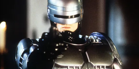 Un personnage en armure métallique futuriste pointant une arme.