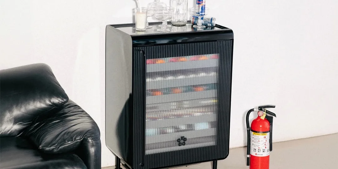 Un petit frigo moderne près d'un canapé et un extincteur.