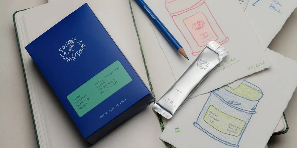 Bloc-notes avec croquis, boîte bleue et emballage argenté sur la table.