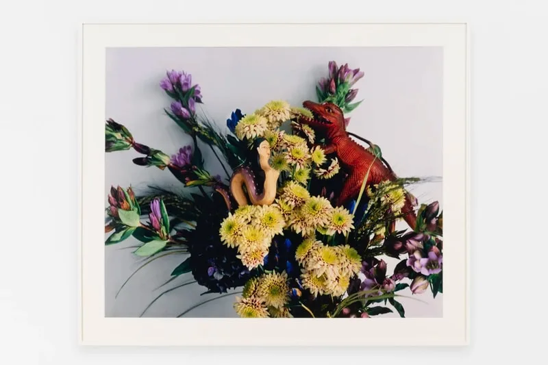 Bouquet fleurs avec figurines, dinosaure et femme, sur fond neutre.