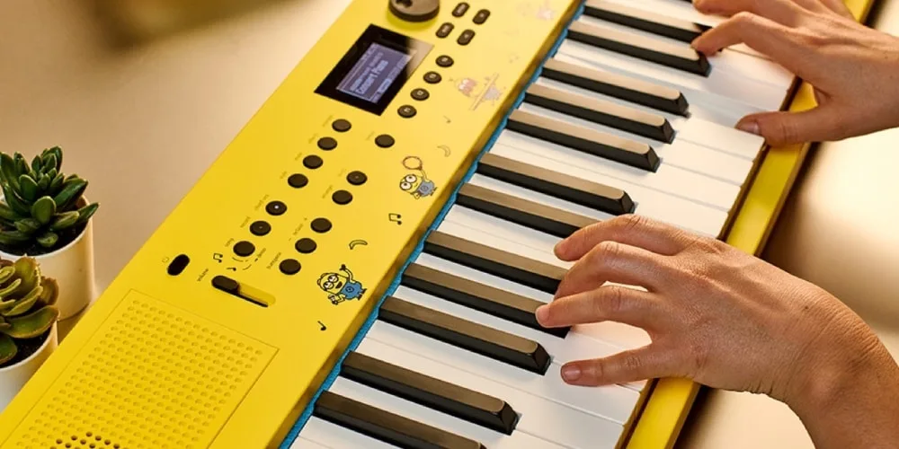 Clavier jaune avec des dessins animés, mains jouant.