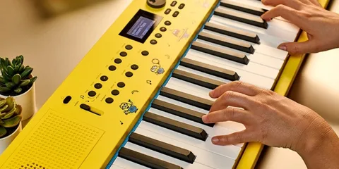 Clavier jaune avec des dessins animés, mains jouant.