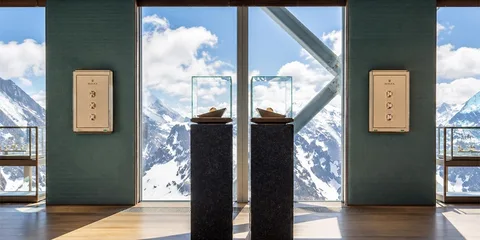 Vue sur montagnes enneigées depuis intérieur, avec présentoirs et fenêtres.