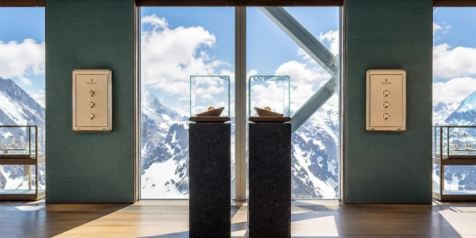 Vue sur montagnes enneigées depuis intérieur, avec présentoirs et fenêtres.