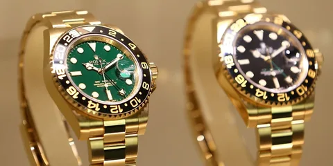 Deux montres en or avec cadrans vert et noir, exposées en vitrine.