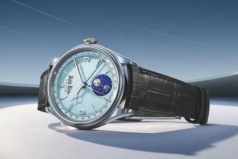 Montre élégante avec fond bleu ciel et bracelet en cuir noir.