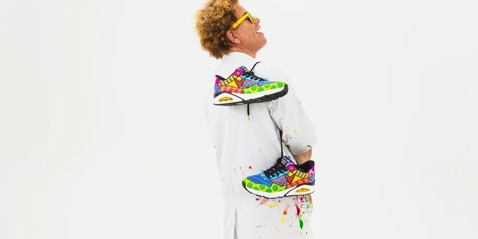 Homme avec lunettes jaunes et chaussures colorées, fond blanc.