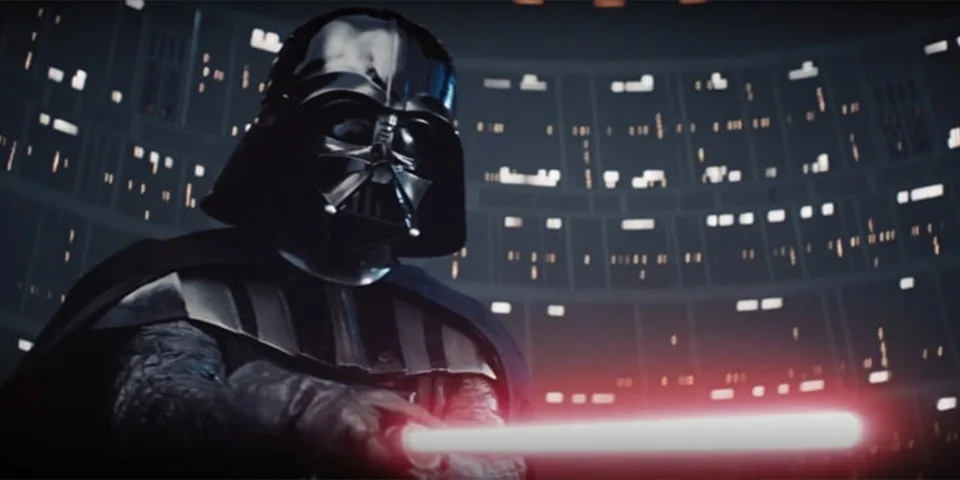 Personnage en armure noire avec un sabre laser rouge, dans un environnement sombre.