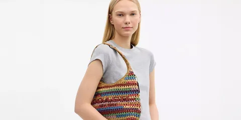 Femme avec un sac crocheté multicolore sur l'épaule.
