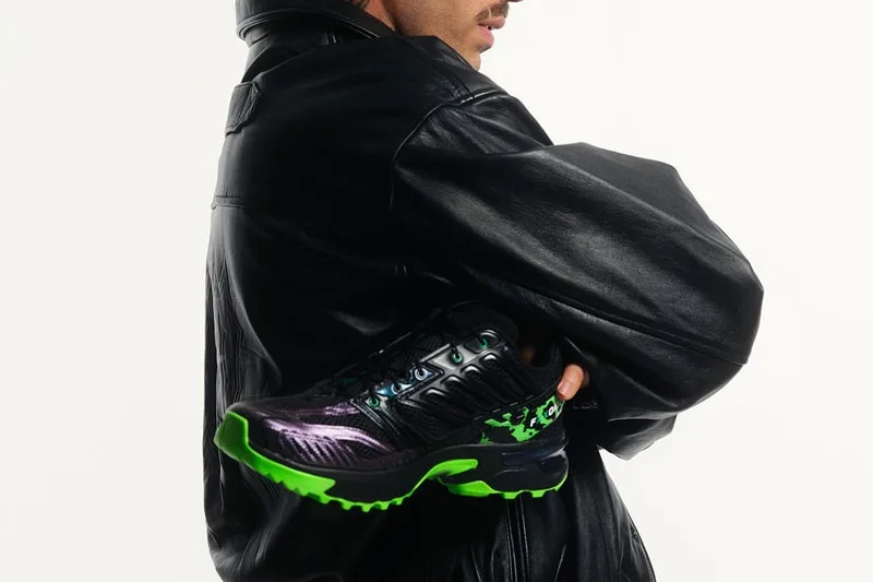 Personne en veste cuir tenant des baskets noires et vertes.