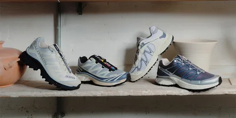 Quatre chaussures de sport alignées sur une étagère en bois.