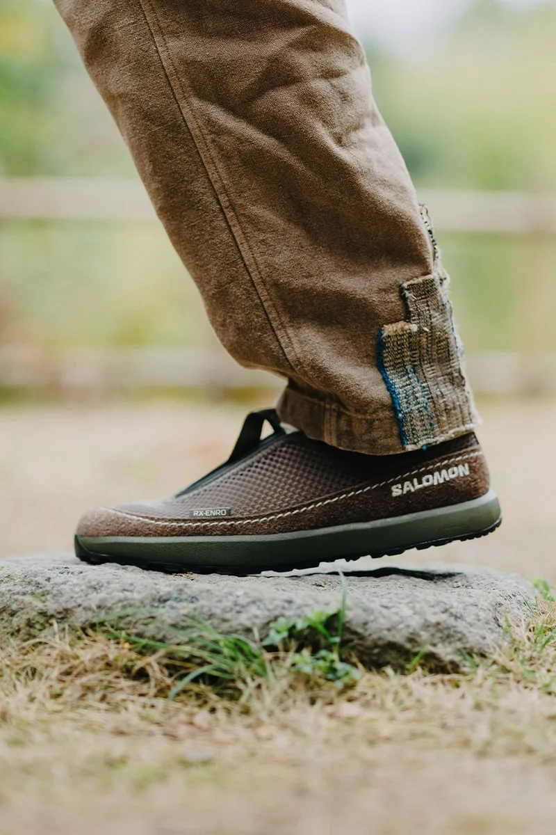 Chaussure marron Salomon sur un rocher, pantalon beige.