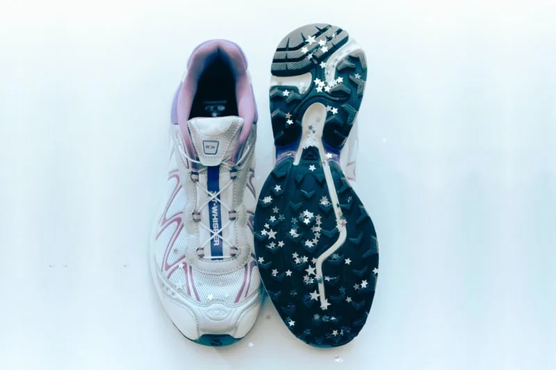 Chaussures de sport blanches et violettes avec semelles étoilées noires.
