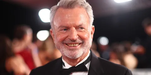 Homme souriant en smoking lors d'un événement glamour.