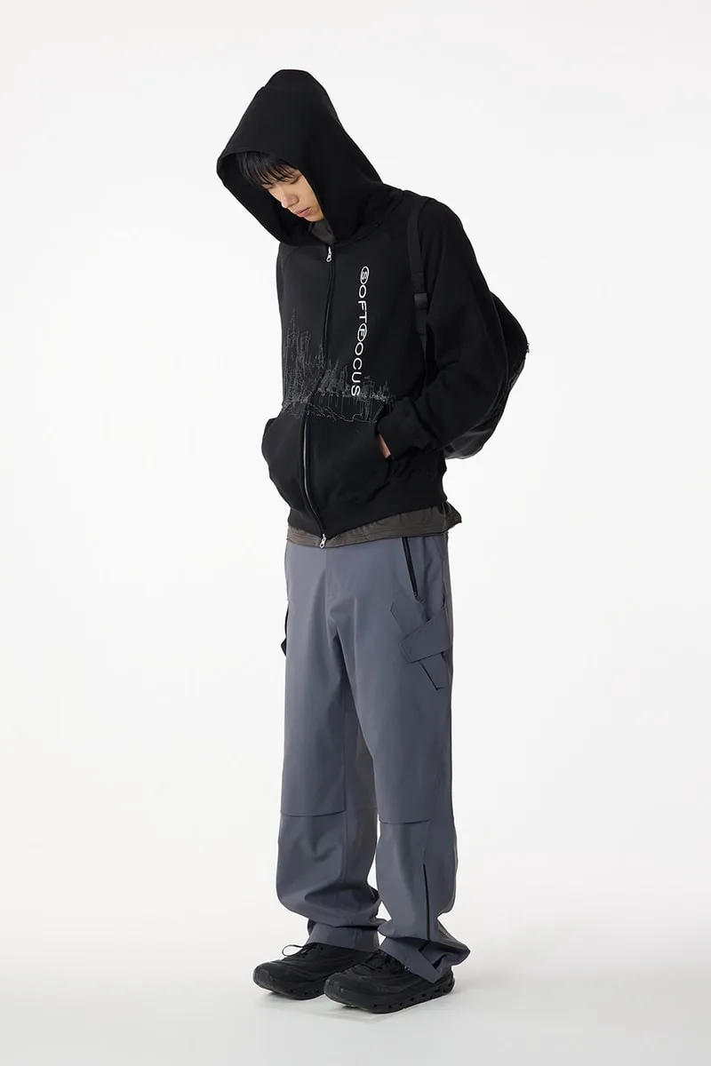 Personne en sweat à capuche noir et pantalon gris, style décontracté.