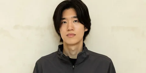 Homme asiatique avec veste grise, fond neutre.
