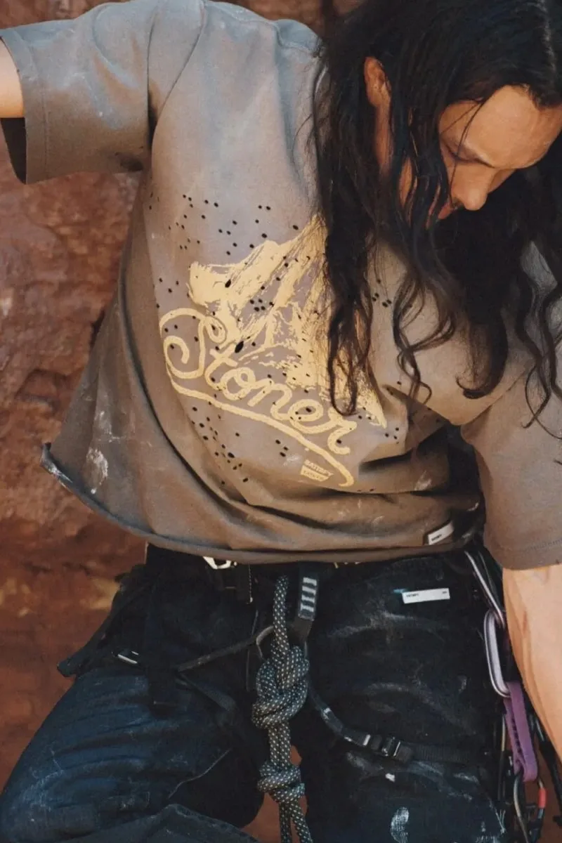 Homme grimpeur avec t-shirt Stoner et harnais d'escalade.