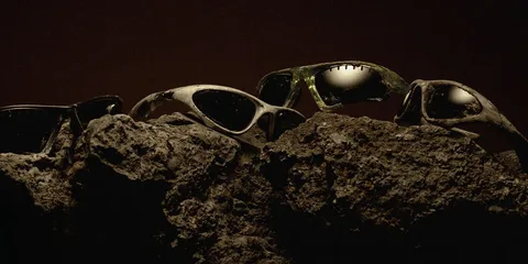 Lunettes de soleil posées sur des rochers, ambiance sombre.