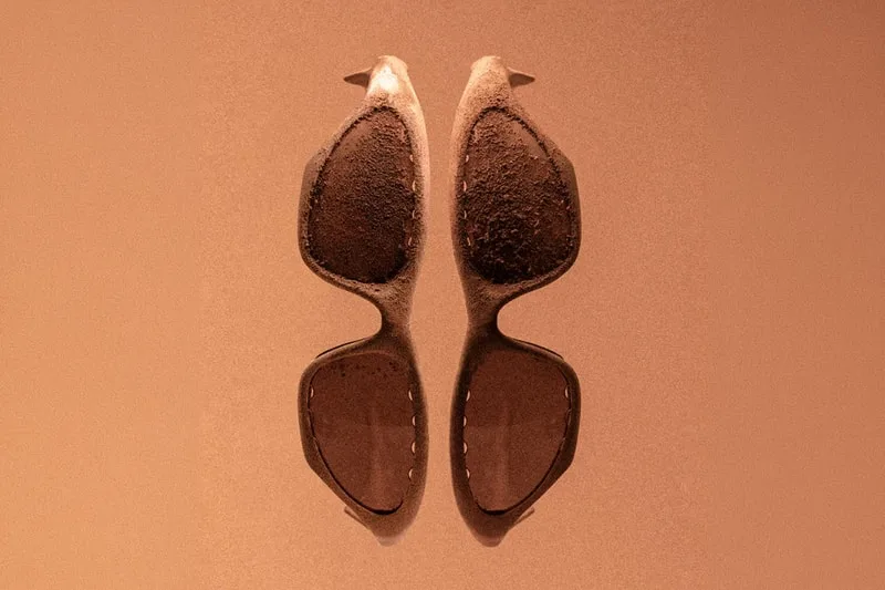 Lunettes de soleil symétriques sur fond brun sable.