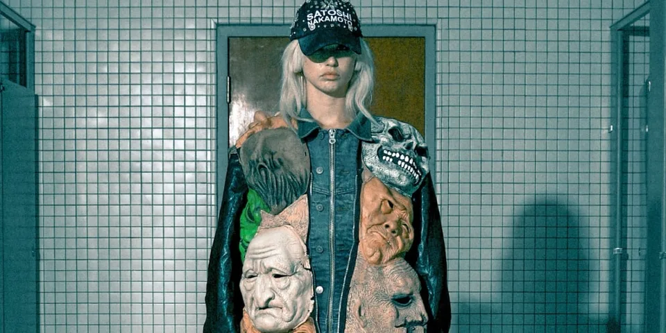 Personne avec veste artistique et casquette dans une pièce carrelée.