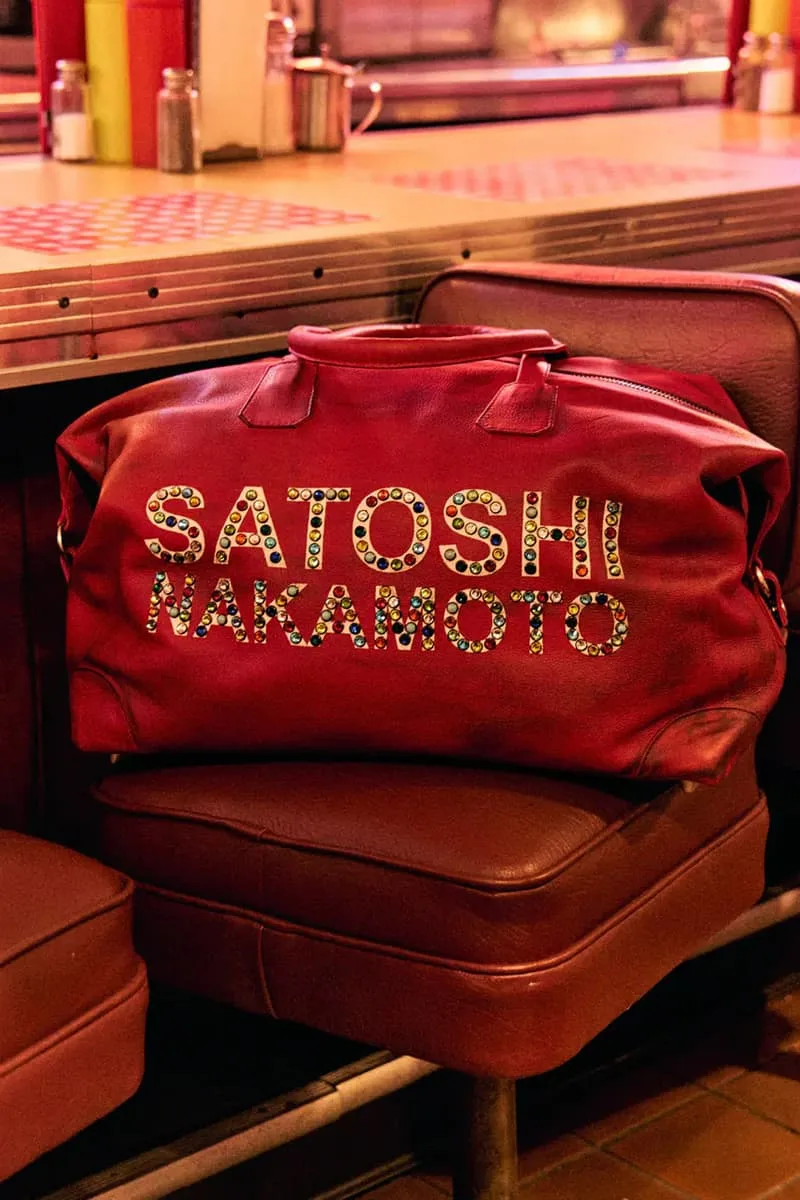 Sac rouge avec texte 'Satoshi Nakamoto' en strass sur le siège brun.