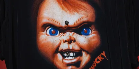 Image du visage menaçant d'une poupée rouge et bleue, nom "Chucky" visible.