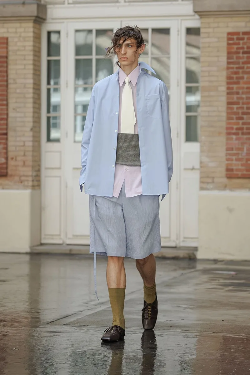Homme en tenue élégante décontractée, shorts et chemise bleue.
