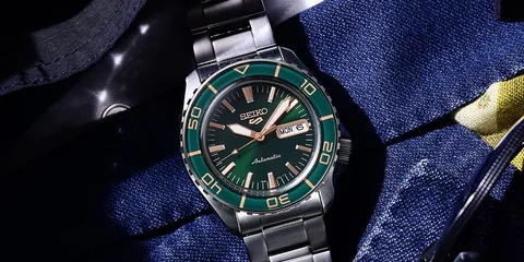Montre Seiko avec cadran vert et bracelet métal sur un tissu bleu.