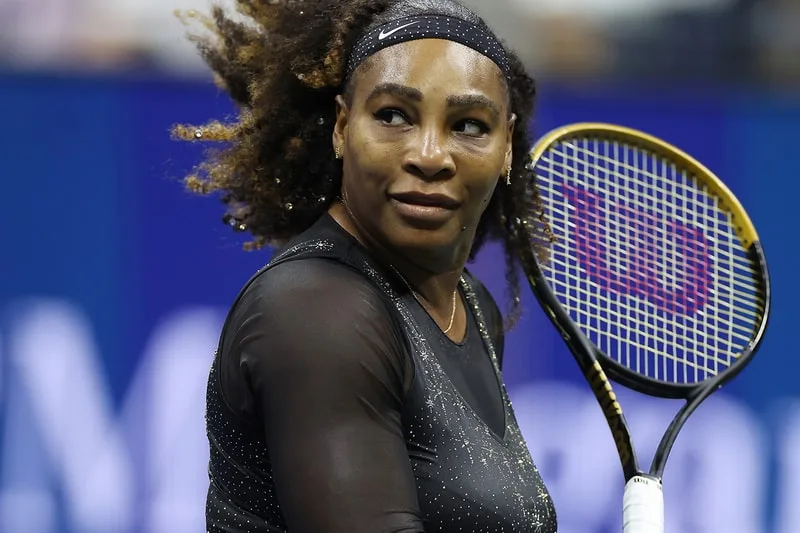 Joueuse de tennis avec raquette sur le terrain, cheveux bouclés au vent.