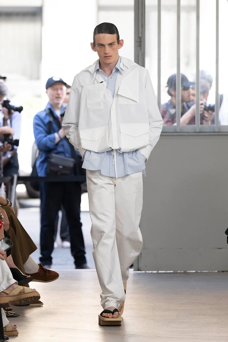 Homme en tenue blanche décontractée sur le podium lors d'un défilé de mode.