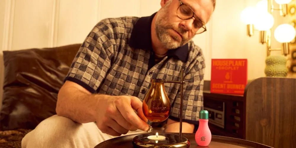 Homme allumant un brûleur à parfum Houseplant dans un salon cosy.