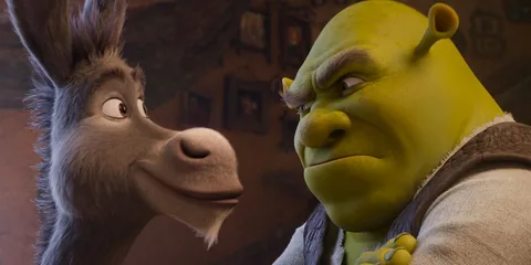 Un ogre vert et un âne parlent dans une pièce.