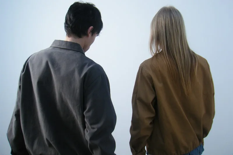 Deux personnes de dos portant des vestes grises et brunes.
