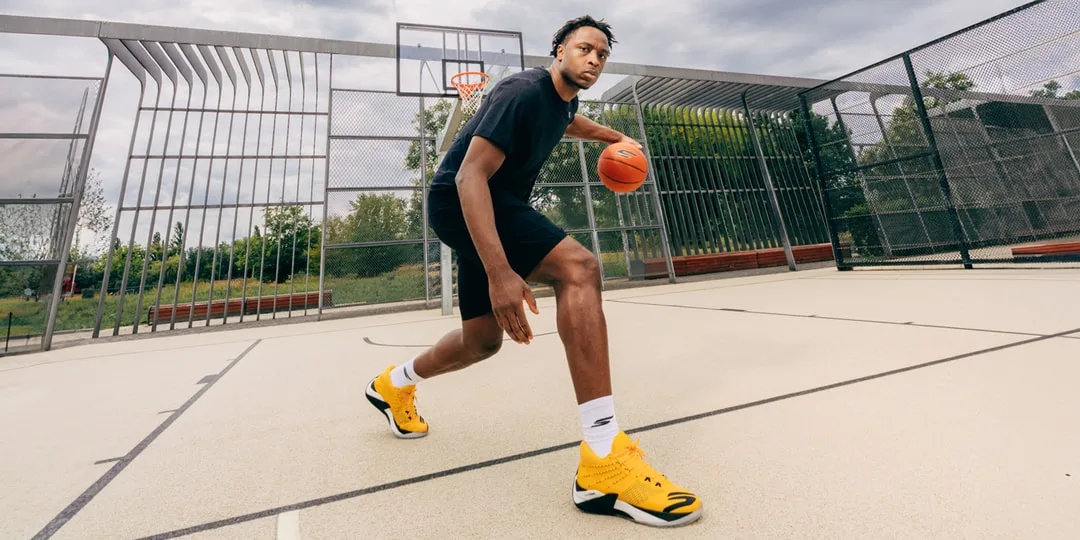 Joueur de basket dribblant sur un terrain extérieur.