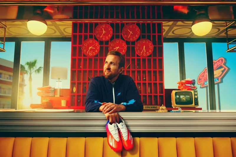 Homme tenant des chaussures rouges dans un décor rétro avec horloges rouges.