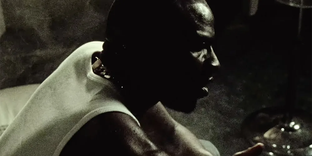 Homme de profil assis dans une pièce sombre.