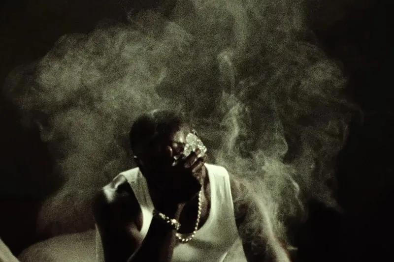 Homme fumant avec fumée tourbillonnante, ambiance sombre.