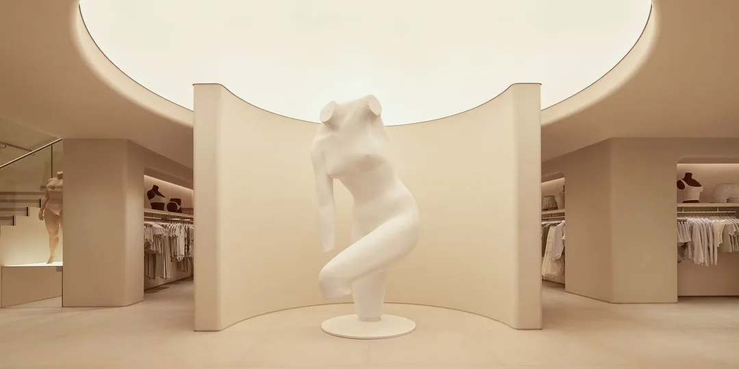 Intérieur moderne avec statue blanche et vêtements exposés.