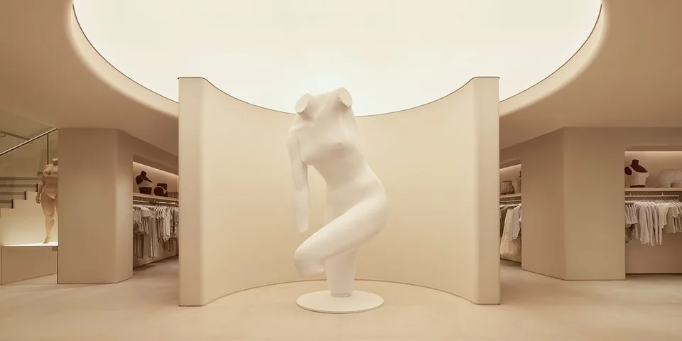 Intérieur moderne avec statue blanche et vêtements exposés.