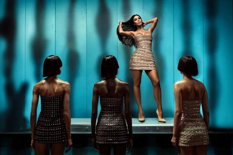 Femme posant devant trois mannequins dans une robe à paillettes.