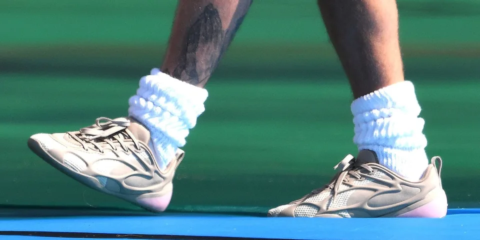 Personne portant des baskets et chaussettes blanches épaisses.