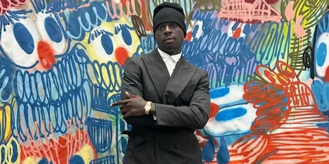 Homme en costume devant un mur coloré et graffiti.
