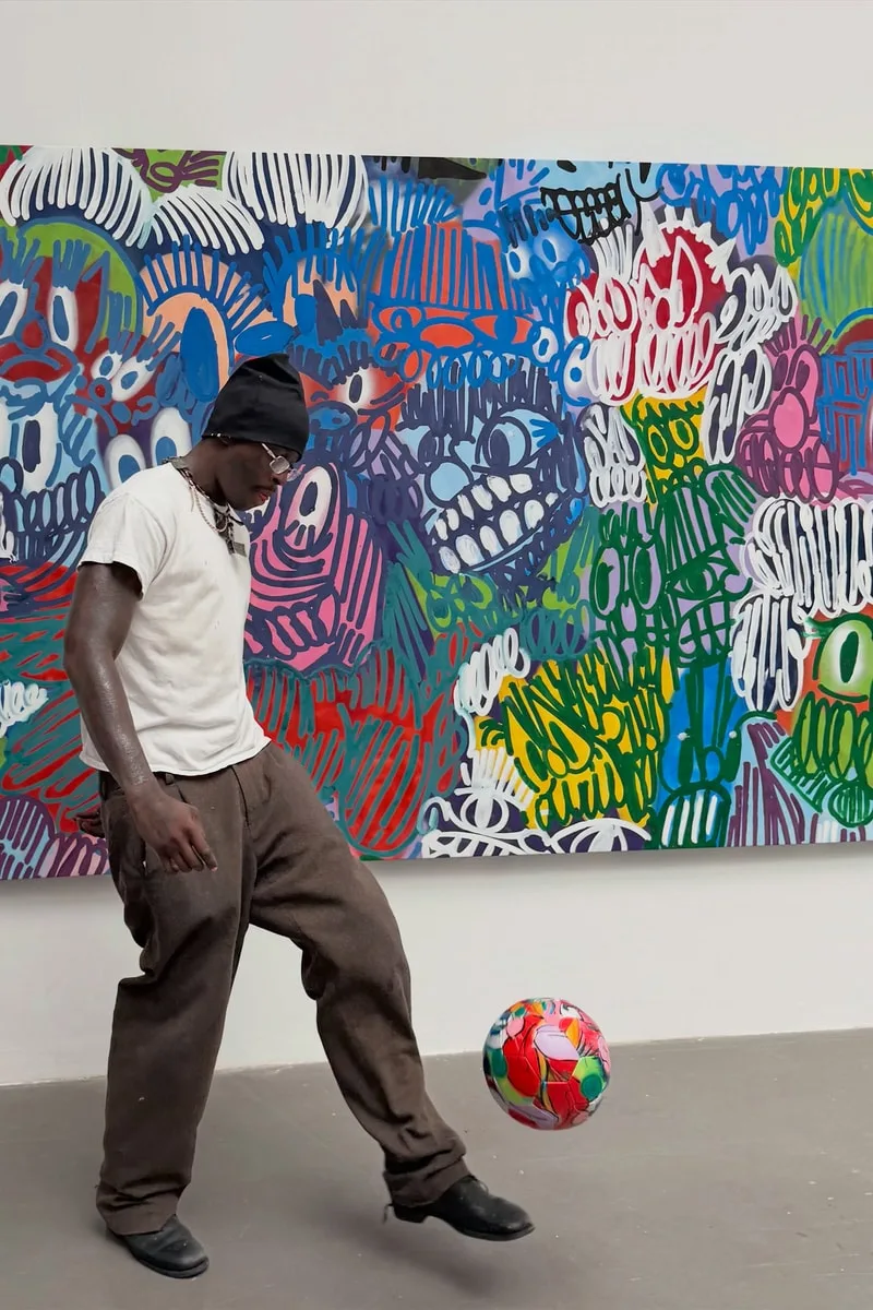 Homme jonglant un ballon devant une peinture colorée dans une galerie.
