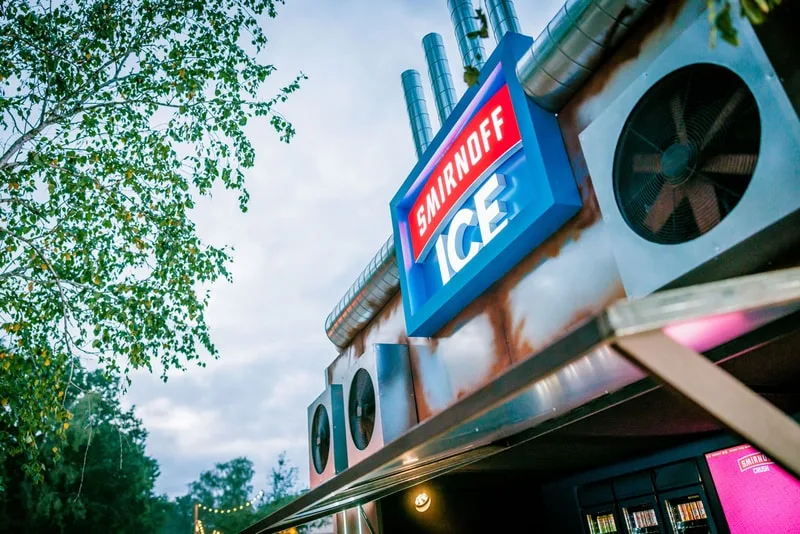 Kiosque avec enseigne Smirnoff ICE et arbres en arrière-plan.