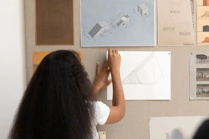 Personne accrochant des dessins géométriques sur un mur.
