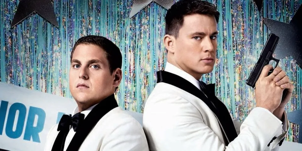 Deux hommes en smoking blanc, dos à dos, avec un fond étoilé.