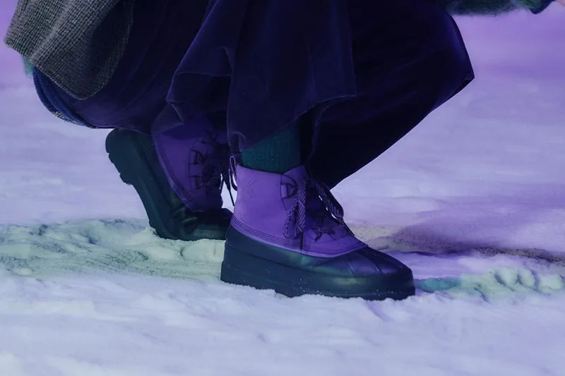 Bottes violettes sur neige dans un éclairage violet.