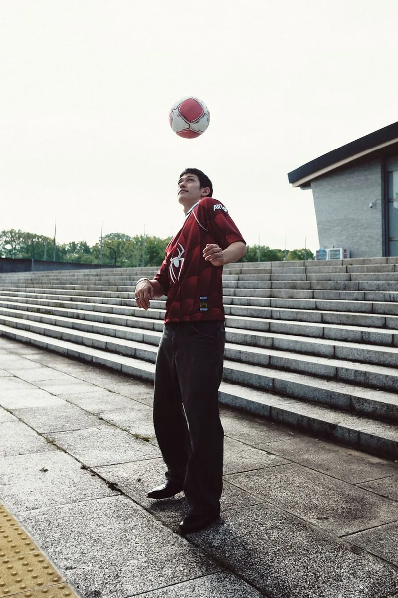 Homme jonglant avec un ballon de football sur des marches extérieures.