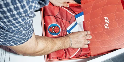 Personne ouvrant une boîte avec un maillot de basket rouge à l'intérieur.
