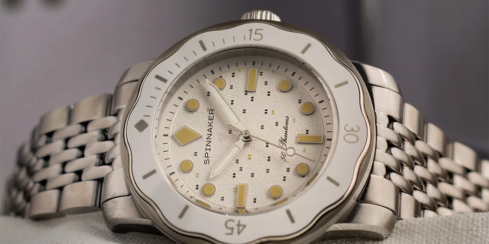 Montre en acier inoxydable avec cadran blanc et aiguilles jaunes, bracelet à maillons.